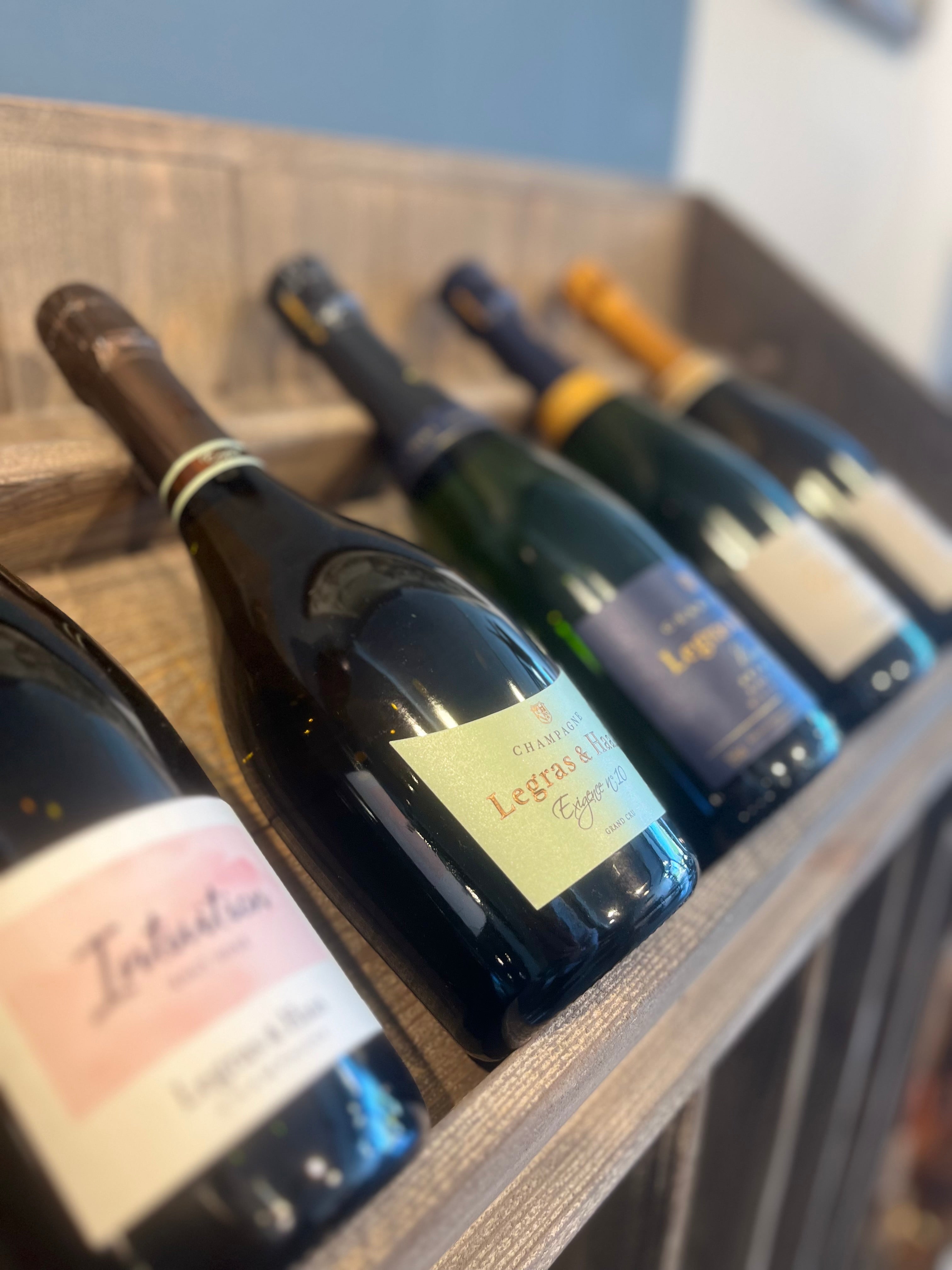 Champagner Begleitung I pairing - An elegant display of various champagne bottles on a wooden rack, showcasing a premium selection for special occasions.