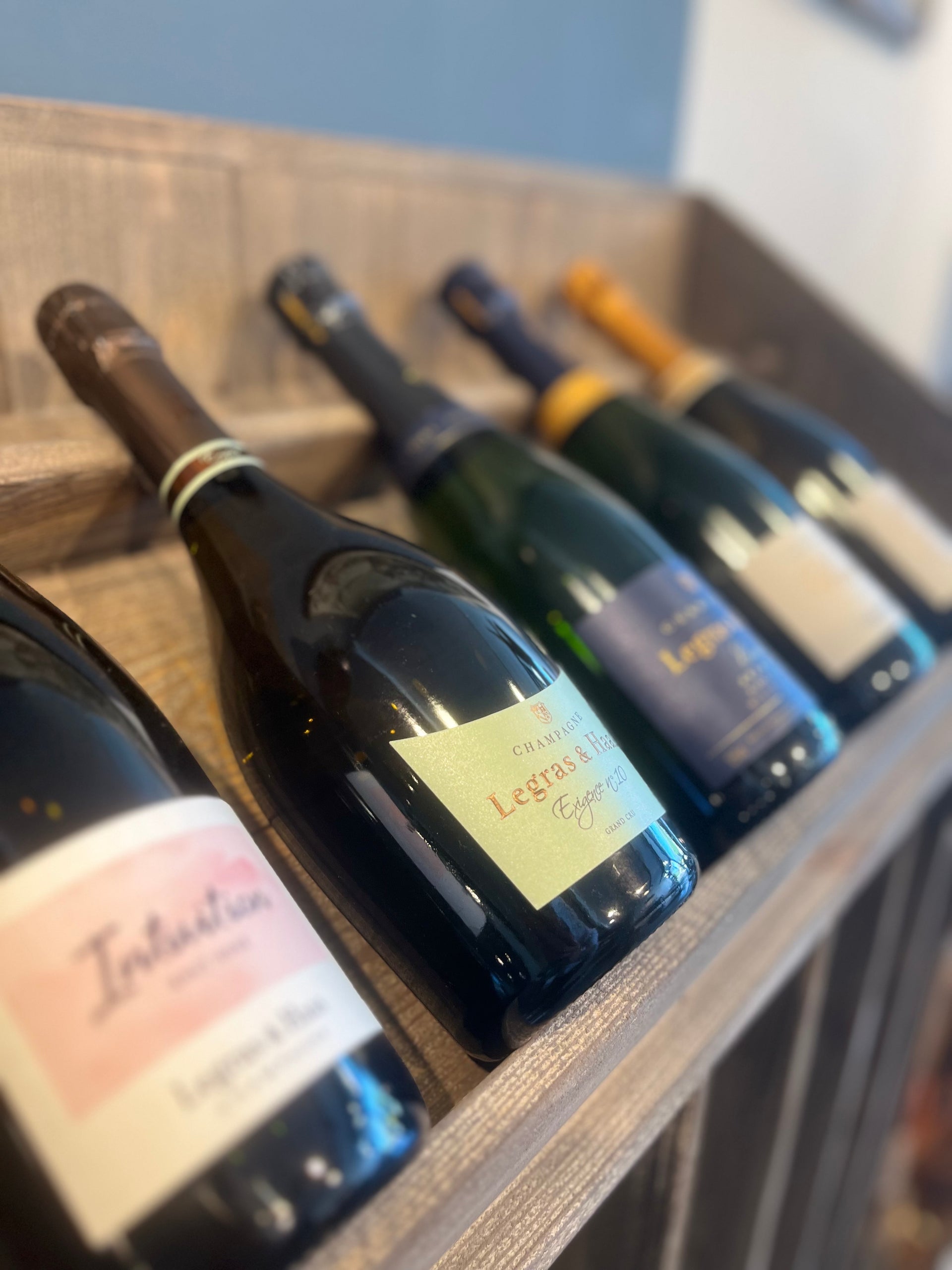 Champagner Begleitung I pairing - An elegant display of various champagne bottles on a wooden rack, showcasing a premium selection for special occasions.